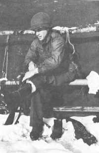 Infantryman wearing a field 
jacket M-1943 tries on a new pair of shoepacs with wool ski socks, January 1945