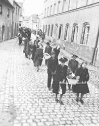 German civilians, forced to 
disinter victims of a concentration camp from a mass grave, carry them through the streets for reburial