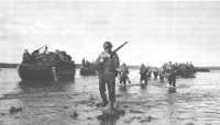 Troopers of the 112th 
Cavalry wade ashore at Arawe as Marine LVTs carry in supplies on 15 December 1943