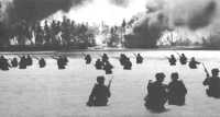 Soldiers of 2/165 wade 
toward the lagoon beach at Butaritari, as smoke rises from oil dumps hit by naval gunfire