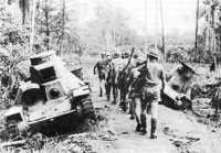 Australian riflemen passing 
abandoned Japanese tanks bogged down near No