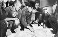 Korean Laborers, captured 
on Kwajalein, point out the location of enemy positions on a map