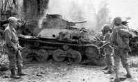 Burning Japanese tanks 
are checked by 127th Infantry troops north of Lonoy