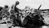 A knocked-out Japanese 
light tank is examined by a 96th Division soldier