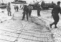 Engineers anchor reinforced 
track for vehicles coming ashore at Omaha