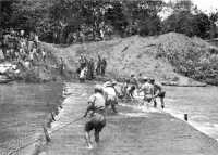 Filipinos help construct a 
road across a ford in the Santa Cruz river, Luzon