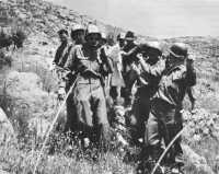 Italian civilians help 
carry a casualty down a mountain near Terracina